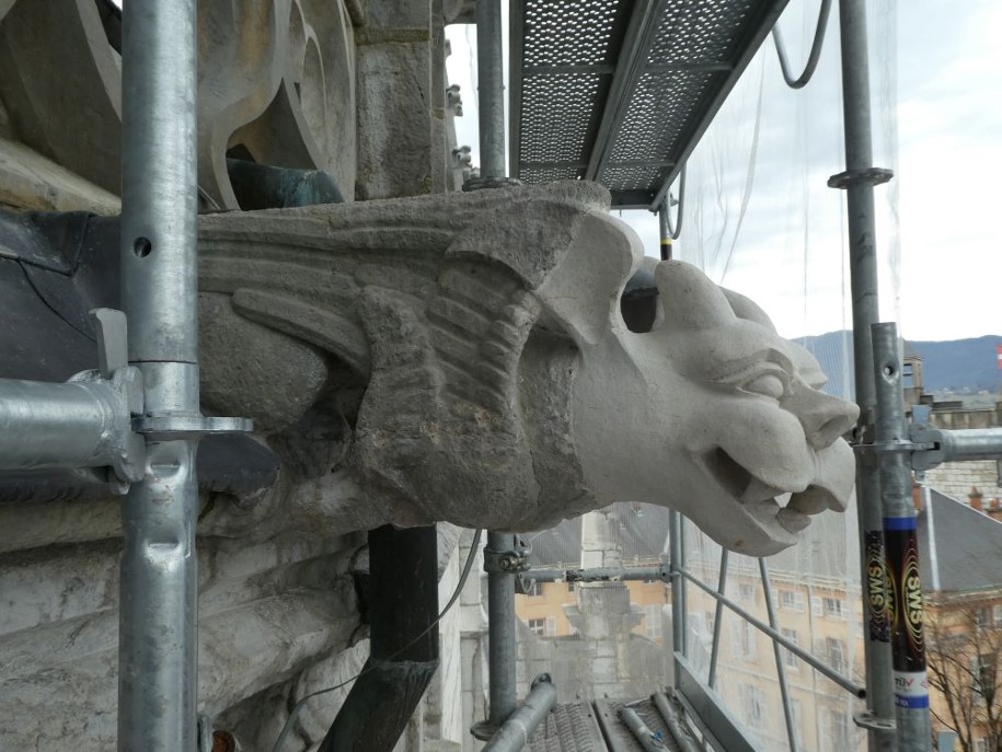 Gargouille a tête de chien. Le sculpteur termine son travail sur place. Une patine est appliquée afin de la protéger de la pollution et des aléas climatiques. La pierre neuve prendra progressivement la teinte du corps.