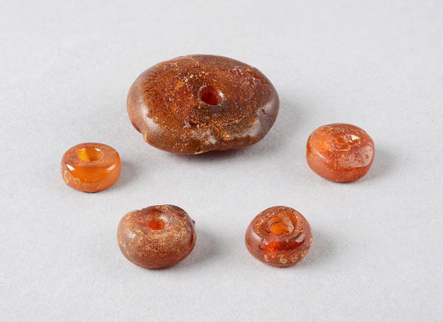 Photo de cinq perles d'ambre de l'âge du Bronze, issues du lac du Bourget, collection Musée Savoisien