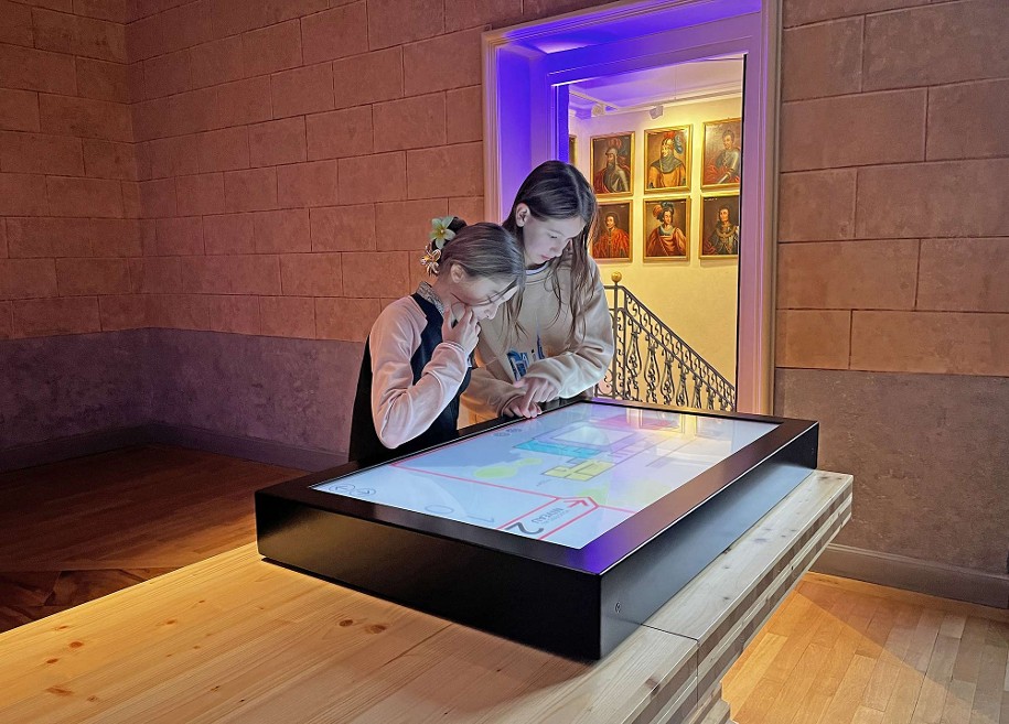 Photographie de deux adolescentes en train d'utiliser une borne multimédia dans le Musée Savoisien