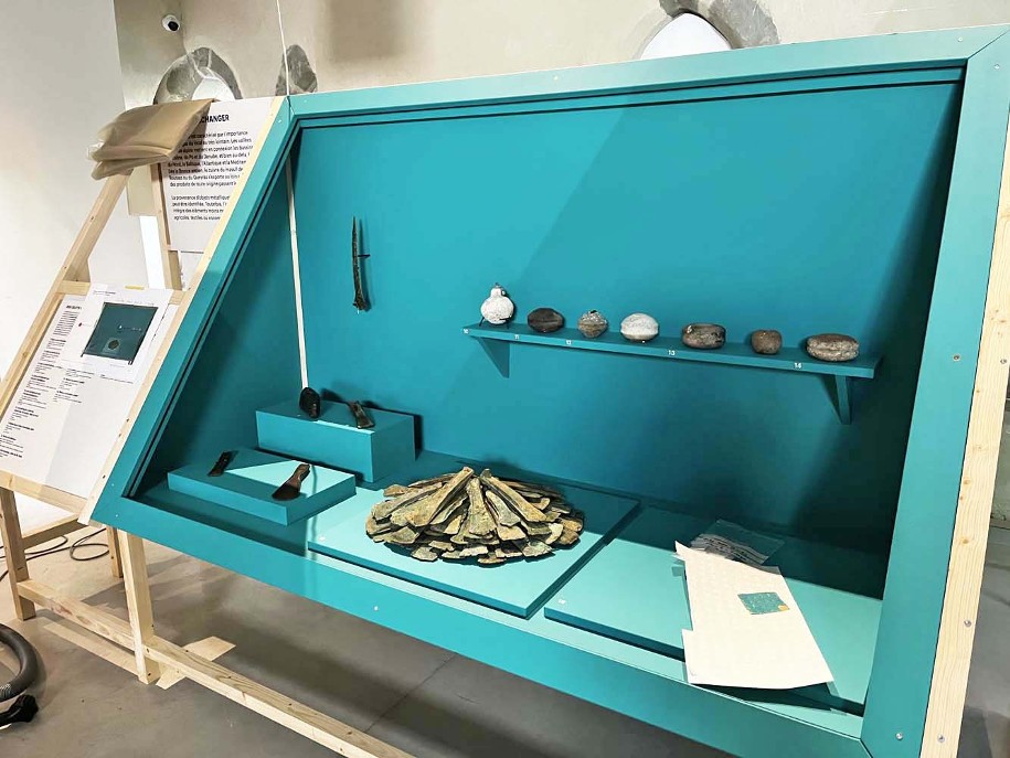 Photo du montage de l'exposition temporaire Bronze, l'âge retrouvé au Musée Savoisien à Chambéry : vue d'une vitrine remplie d'objets