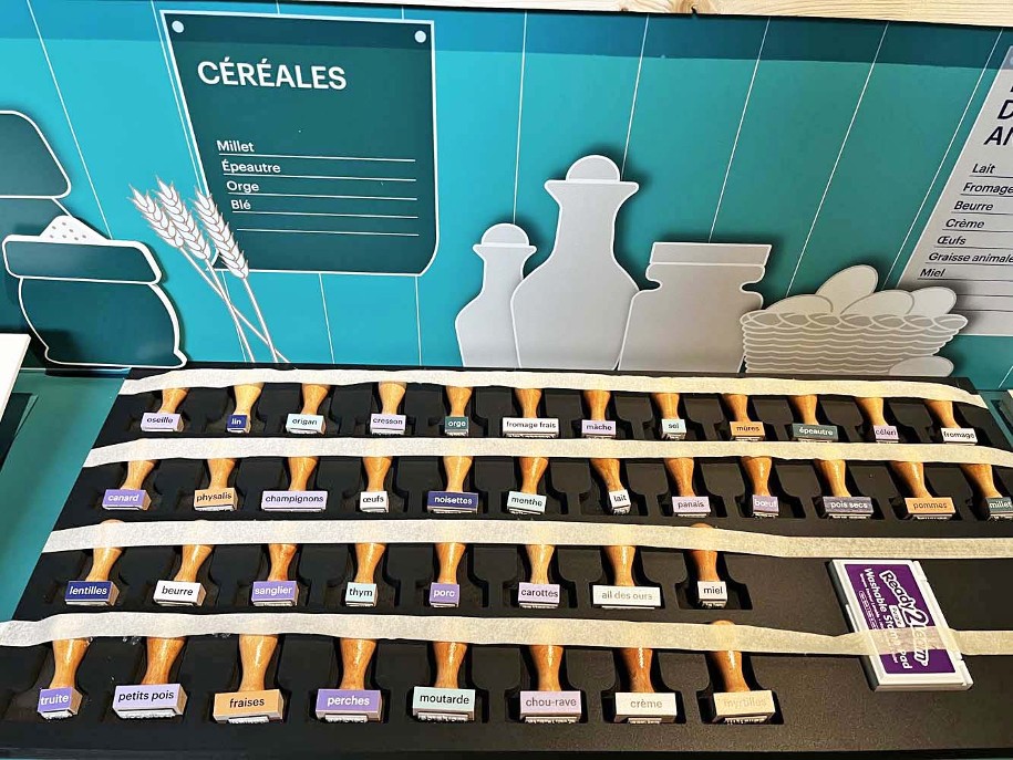 Photo du montage de l'exposition temporaire Bronze, l'âge retrouvé au Musée Savoisien à Chambéry : tampons portant le nom d'ingrédients utilisés en cuisine à l'âge du Bronze pour un atelier